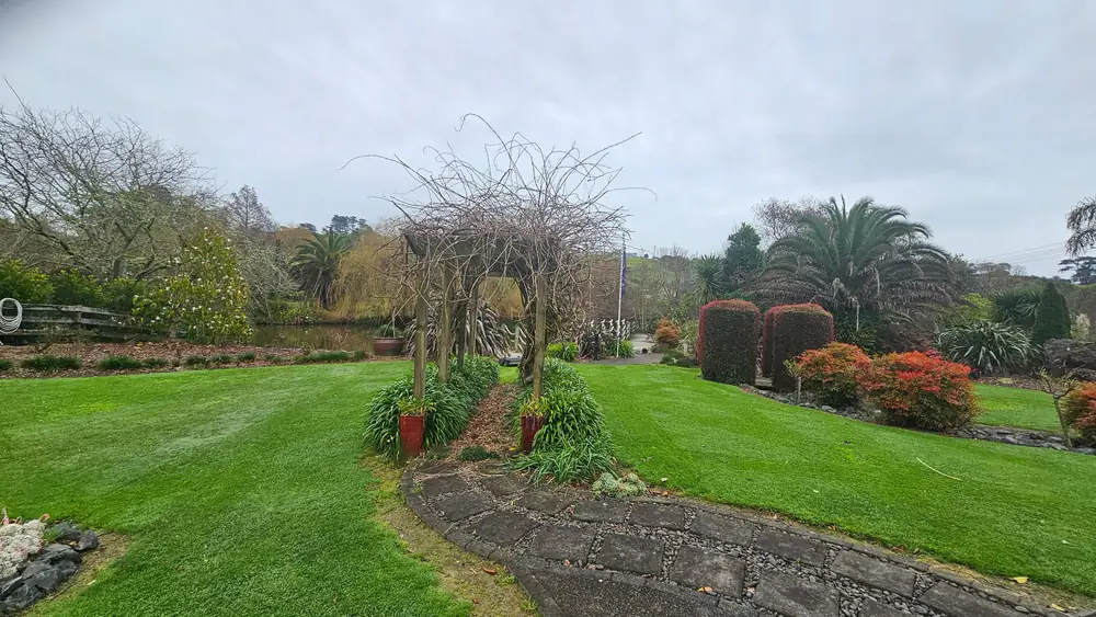 A large landscaped lawn with curved garden beds and mature planting